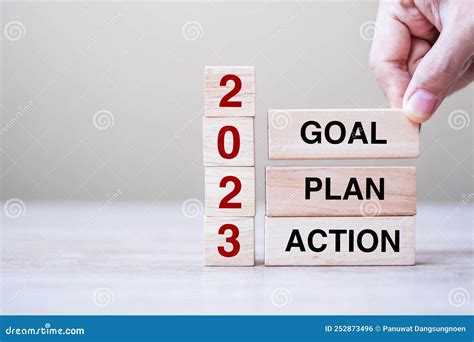 Hand Holding Wooden Block With Text 2023 GOAL PLAN And ACTION On Table