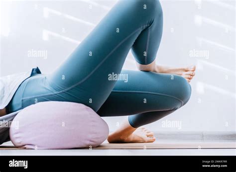 Woman Doing Yin Yoga Passive Hip Stretch Exercises On Bolster Stock