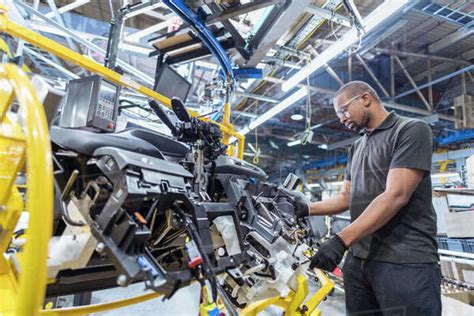 Worker Assembling Dashboard On Production Line In Car Factory Stock