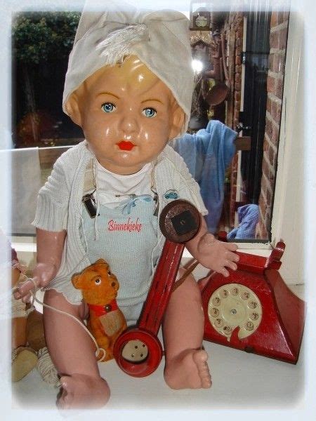 An Old Fashioned Doll Sitting On Top Of A Table Next To A Teddy Bear