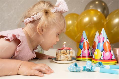 Premium Photo A Twoyearold Girl Blows Out A Candle On A Birthday Cake