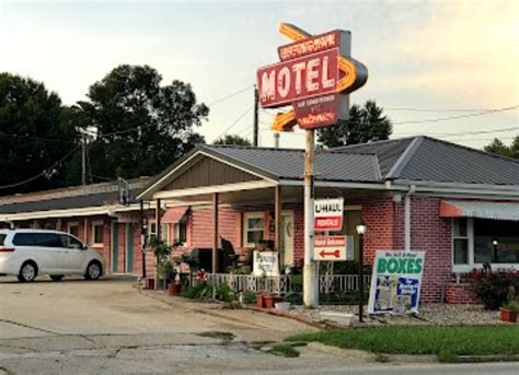 a motel with cars parked in front of it on the side of the road next to ...