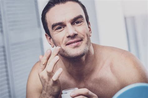 Close Up Of Delighted Man That Applying Cream On Skin Stock Photo