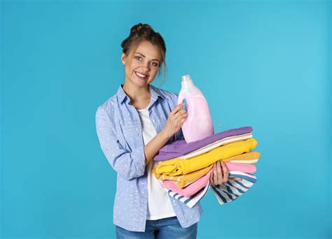 Happy Young Woman Holding Clean Clothes And Laundry Detergent Stock