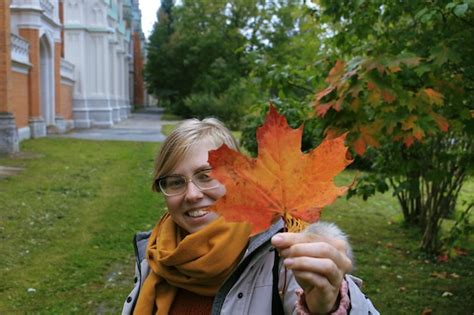 Premium Photo Portrait Of Smiling Woman Holding Maple Leaf During Autumn