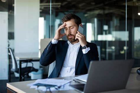 Empresário masculino preocupado falando no celular e tocando a cabeça