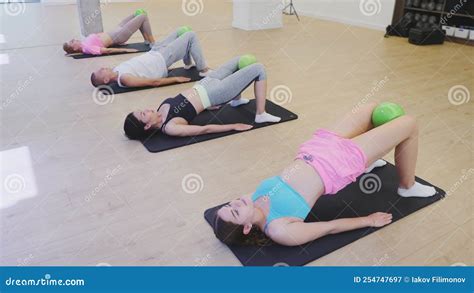 Group Of People Doing Hip Bridge Exercise With Small Pilates Ball Stock