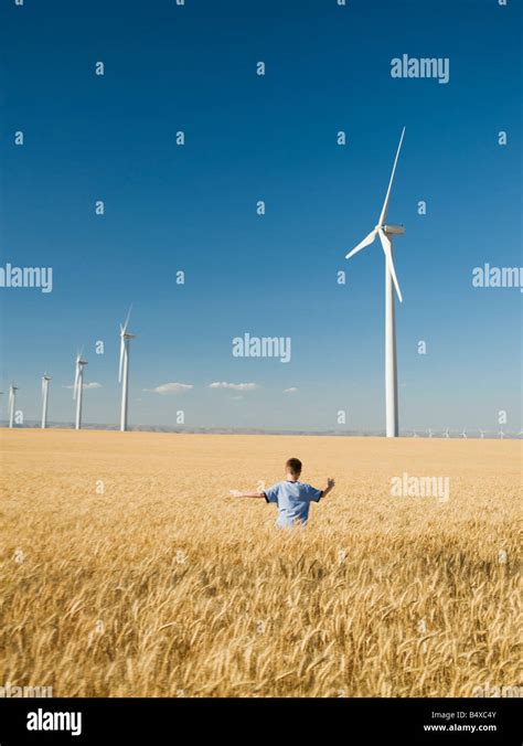 Boy Running Through Field On Wind Farm Stock Photo Alamy