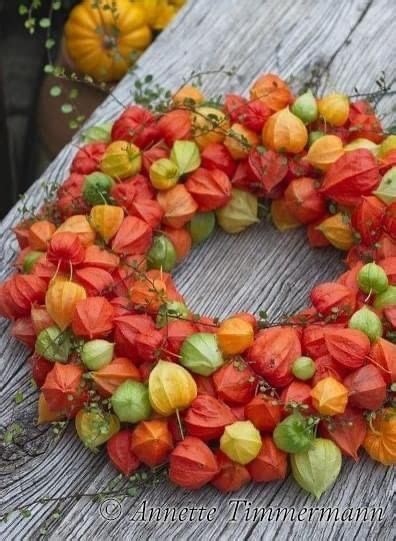 A Wreath Made Out Of Flowers On Top Of A Wooden Table With Pumpkins In