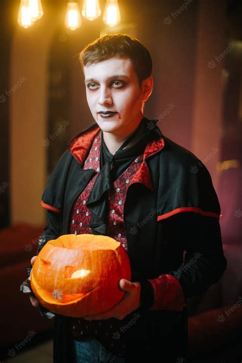 Premium Photo Guy In A Halloween Costume Of Count Dracula Holds A Carved Pumpkin In His Hand