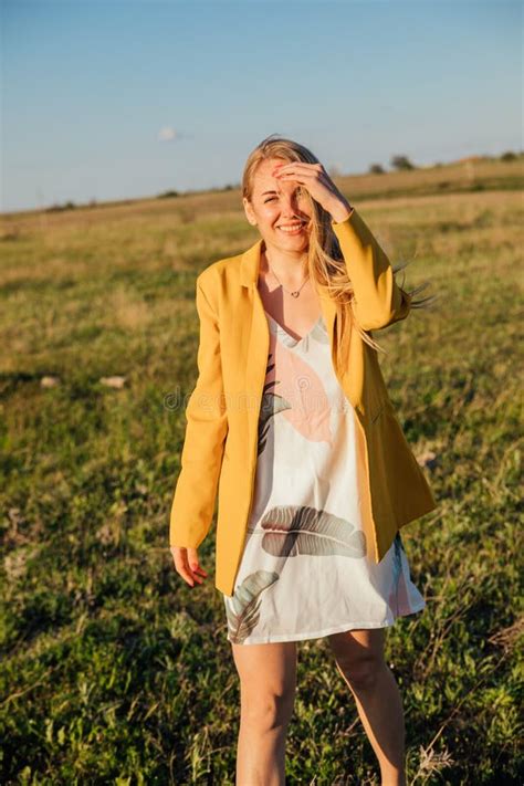 Blonde Woman Walking Through A Green Field At Sunset Stock Image