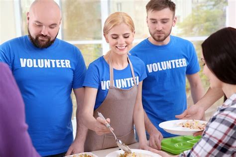 Jóvenes voluntarios sirviendo comida a personas sin hogar Foto Premium