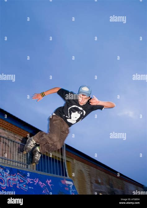 18-year old male doing aggressive inline skating tricks on quarter pipe ...