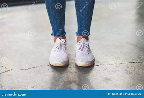 Una Mujer Con Zapatillas De Jean Y Blancas En El Suelo De Cemento Foto De Archivo Imagen De