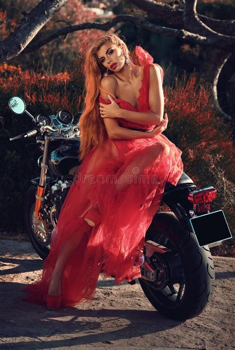 Beautiful Woman In Red Fluffy Dress Posing Seated On Motorcycle Stock