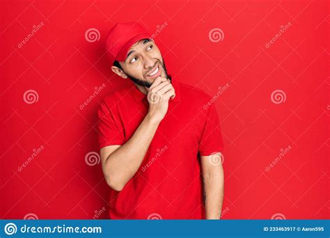 Hispanic Man With Beard Wearing Delivery Uniform And Cap Thinking