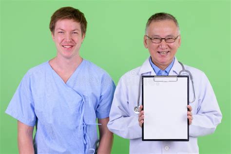 Happy Mature Japanese Man Doctor With Scandinavian Man Patient Showing