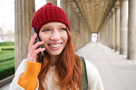 Portrait d une fille européenne rousse au chapeau rouge passe un appel