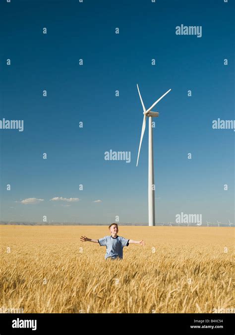 Boy Running Through Field On Wind Farm Stock Photo Alamy