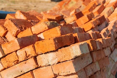 Os tijolos vermelhos são empilhados no canteiro de obras Os tijolos