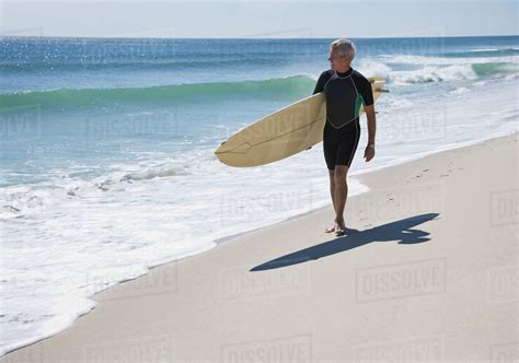 Man Carrying Surfboard At Beach Stock Photo Dissolve