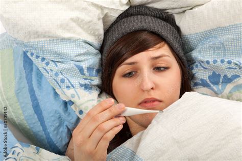 Das junge Mädchen liegt krank im Bett und misst Fieber Stock Photo