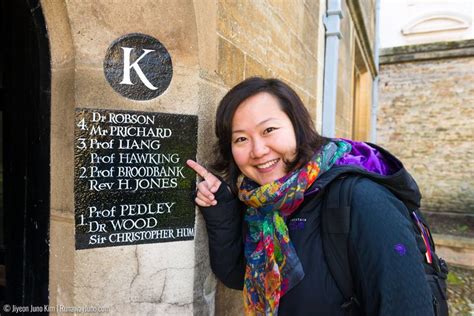 a woman standing next to a stone wall with a plaque on it's side