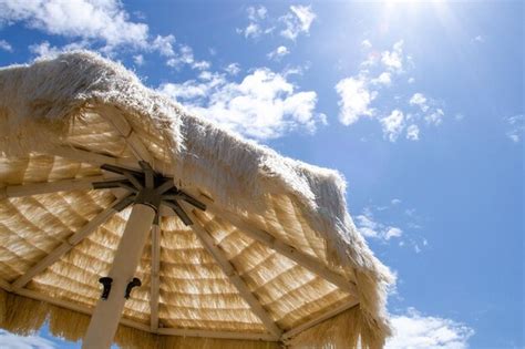 Guarda chuva de palha branca na praia contra o céu Foto Premium