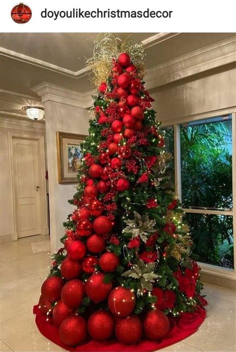 A Christmas Tree Is Decorated With Red Balls And Greenery For The