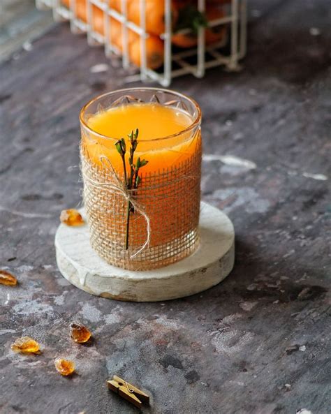 A Glass Filled With Orange Juice Sitting On Top Of A Table