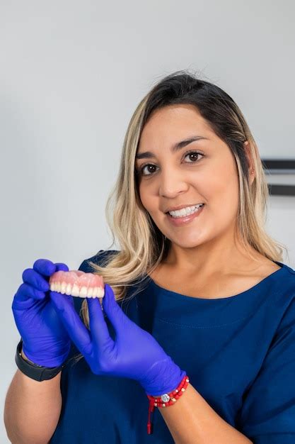 Sorrindo Dentista Feminino Exibindo Prótese Dentária Em Seu Consultório