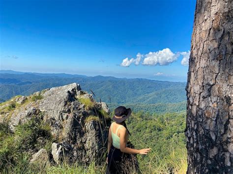 Una niña de pie en el borde del acantilado y mirando las montañas doi