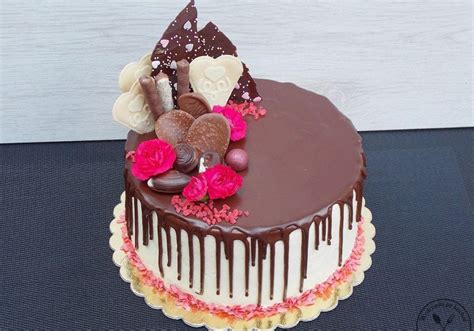 A Chocolate Cake With Flowers And Hearts On Top Is Sitting On A Black