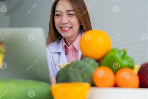 Portrait Of Asian Smiling Female Nutritionist Typing On Laptop Computer