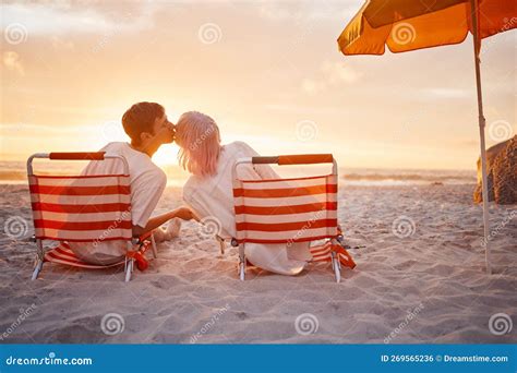 Couple Kiss And Beach Chairs By A Ocean Sunset With Love Happiness And Care On Vacation Sea