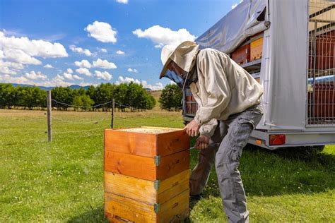 Premium Photo Beekeeper Inspecting A Beehive While Wearing A