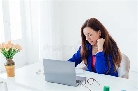 Brunette Woman In Blue Business Suit At Desk With Laptop Online Stock