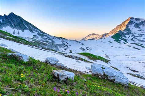 Premium Photo The Snowdrifts And Green Grass On Top Of Mountains In