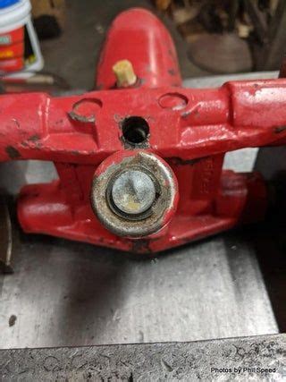 an old red plane sitting on top of a piece of metal in a shop or workshop