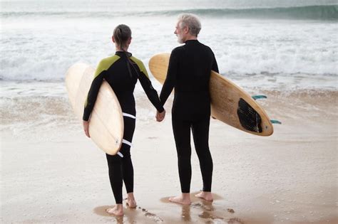 Back View Of Aged Couple Enjoying Walk With Surfboards Sporty Grey