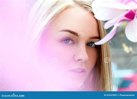 Seductive Blonde Female With Blue Eyes In Blooming Pink Flowers Stock