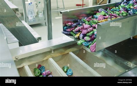 Candy factory. Sweets spilling from conveyor. Bunch of wrapped candies ...