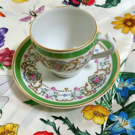 A Cup And Saucer On A Floral Tablecloth