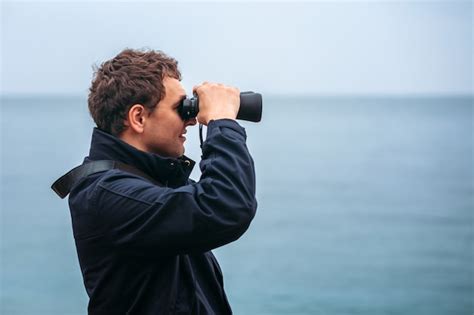 Jeune Homme Regardant Au Loin à Travers Des Jumelles Contre La Mer