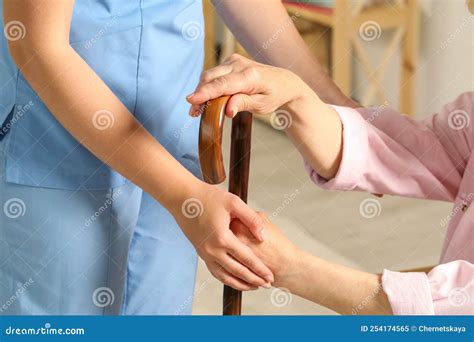 Elderly Woman With Walking Cane And Female Caregiver Indoors Closeup