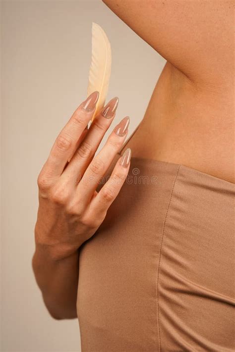 In A Nude Colored Top A Girl Gently Touches Her Underarms With A Feather This Calm And