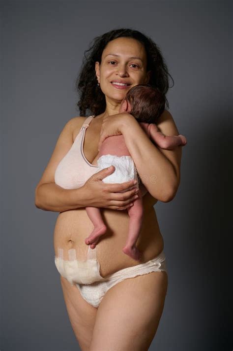 Happy Woman Mother Smiles Looking At Camera Holds Her Newborn Baby And