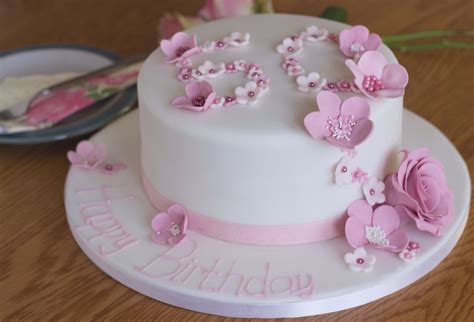 a white cake with pink flowers and the number 50 on it is sitting on a ...