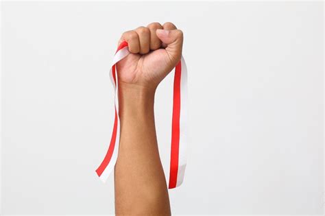 The Hands Of A Man Holding A Red And White Ribbon As A Symbol Of The