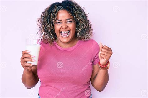 Young African American Plus Size Woman Drinking Glass Of Milk Screaming